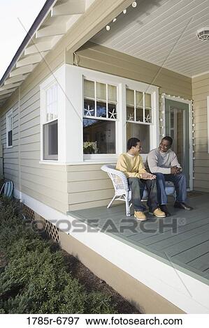 Father and son conversing while sitting on porch View Large Photo Image Stock Photo - Father and son conversing while sitting on porch. Fotosearch