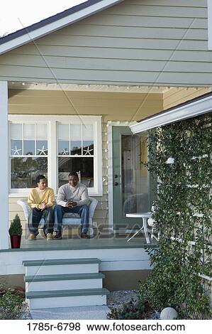 Father and son conversing while sitting on porch View Large Photo Image Stock Photo - Father and son conversing while sitting on porch. Fotosearch
