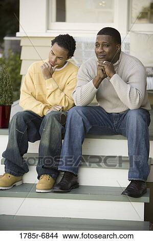 Father sitting with teenage son on front steps of house View Large Photo Image Picture - Father sitting with teenage son on front steps of house. Fotosearch