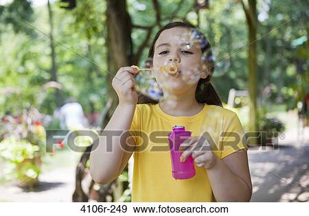 Stock Photo - Girl blowing bubbles in garden. Fotosearch