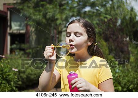 Stock Photography - Girl blowing bubbles in garden. Fotosearch