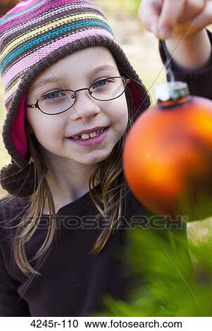 Girl decorating a Christmas tree with an ornament View Large Photo Image Stock Image - Girl decorating a Christmas tree with an ornament. Fotosearch