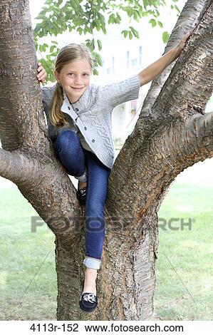 Girl sitting on a tree in a park View Large Photo Image Stock Image - Girl sitting on a tree in a park. Fotosearch