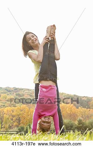 Girls helping friend doing handstand in field View Large Photo Image Stock Image - Girls helping friend doing handstand in field. Fotosearch