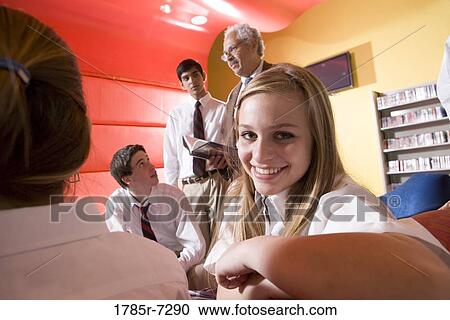 Stock Image - Group of high school students in library with teacher. Fotosearch