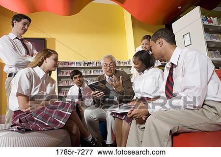 Stock Photo - Group of high school students in library with teacher. Fotosearch