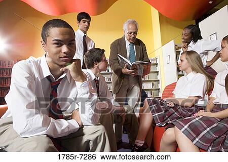 Stock Photograph - Group of high school students in library with teacher. Fotosearch
