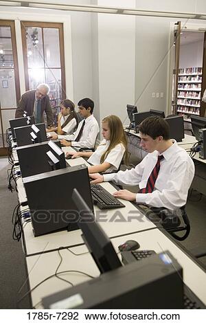 Group of teenage boy and girl students in school uniforms with teacher in a computer lab View Large Photo Image Stock Image - Group of teenage boy and girl students in school uniforms with teacher in a computer lab. Fotosearch