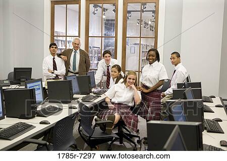 Stock Photo - Group of teenage boy and girl students in school uniforms with teacher in a computer lab. Fotosearch