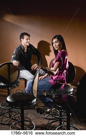 Happy multiracial couple sitting on bar stools View Large Photo Image Stock Photograph - Happy multiracial couple sitting on bar stools. Fotosearch