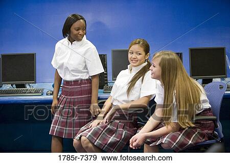 Stock Photo - High school classmates sitting together conversing in computer lab. Fotosearch