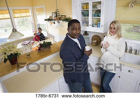 Interracial couple in then kitchen with children in background View Large Photo Image Stock Image - Interracial couple in then kitchen with children in background. Fotosearch