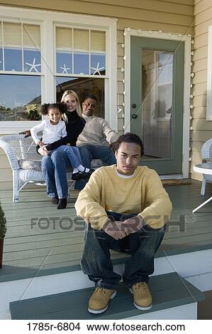 Picture - Interracial family sitting together on porch. Fotosearch