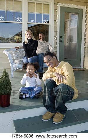 Stock Photograph - Interracial family sitting together on porch. Fotosearch