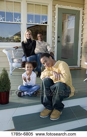 Stock Photography - Interracial family sitting together on porch. Fotosearch