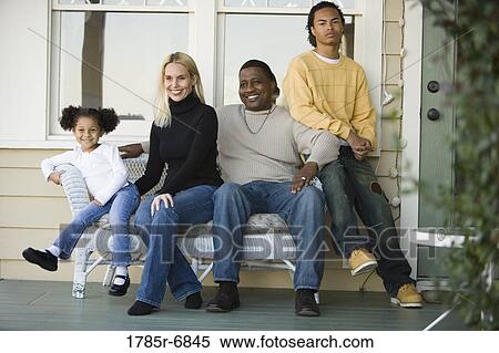 Stock Photography - Interracial family sitting together on porch. Fotosearch