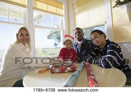 Interracial family wrapping Christmas present View Large Photo Image Stock Photo - Interracial family wrapping Christmas present. Fotosearch