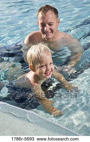 Stock Image - Little boy and father playing in swimming pool. Fotosearch
