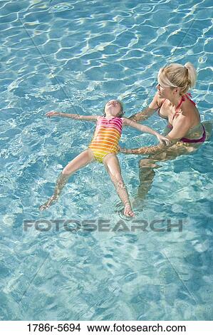 Picture - Little girl learning to float in swimming pool. Fotosearch