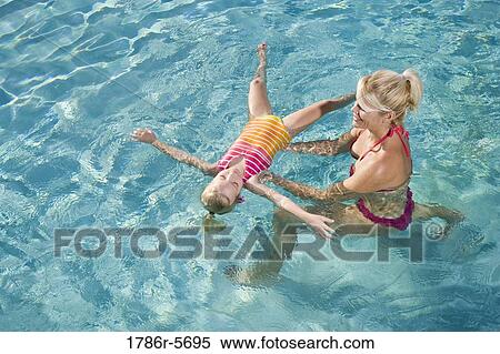 Stock Photography - Little girl learning to float in swimming pool. Fotosearch