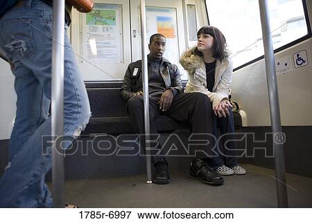 Low angle view of a young inter-racial couple traveling in a mass transit train View Large Photo Image Stock Photo - Low angle view of a young inter-racial couple traveling in a mass transit train. Fotosearch
