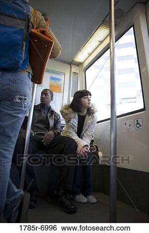 Low angle view of a young inter-racial couple traveling in a mass transit train View Large Photo Image Stock Photograph - Low angle view of a young inter-racial couple traveling in a mass transit train. Fotosearch