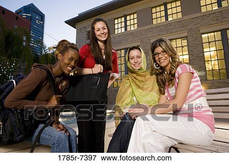 Low angle view of four women friends in conversation, sitting outside a building View Large Photo Image Stock Photo - Low angle view of four women friends in conversation, sitting outside a building. Fotosearch