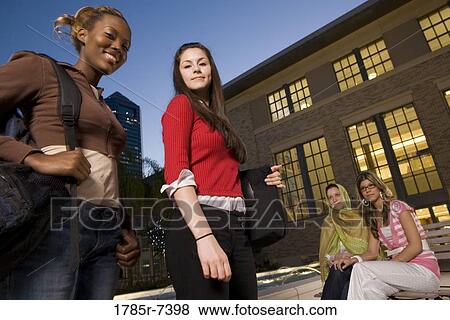 Low angle view of four women friends in conversation, sitting outside a building View Large Photo Image Stock Photo - Low angle view of four women friends in conversation, sitting outside a building. Fotosearch