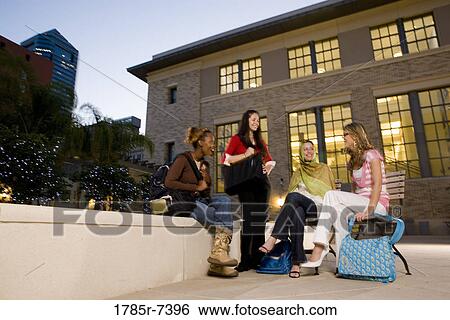 Low angle view of four women friends in conversation, sitting outside a building View Large Photo Image Stock Photograph - Low angle view of four women friends in conversation, sitting outside a building. Fotosearch