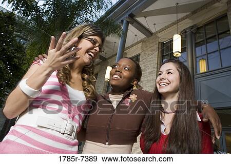 Stock Photo - Low angle view of three young women best friends smiling. Fotosearch