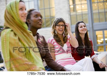 Low-angle view of women sitting together outside a building View Large Photo Image Stock Image - Low-angle view of women sitting together outside a building. Fotosearch