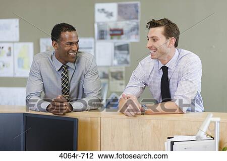 Stock Image - Male co-workers hanging out at office. Fotosearch