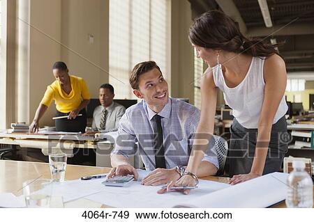 Man and woman talking over plans at desk in office View Large Photo Image Stock Photo - Man and woman talking over plans at desk in office. Fotosearch