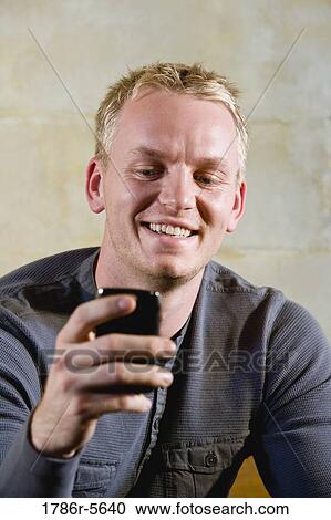 Stock Image - Man holding mobile phone, texting. Fotosearch