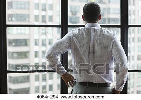 Man looking out on city from his loft apartment View Large Photo Image Picture - Man looking out on city from his loft apartment. Fotosearch