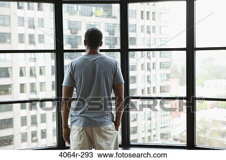Man looking out on city from his loft apartment View Large Photo Image Stock Image - Man looking out on city from his loft apartment. Fotosearch