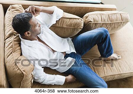 Man relaxing on sofa in loft apartment View Large Photo Image Stock Photo - Man relaxing on sofa in loft apartment. Fotosearch