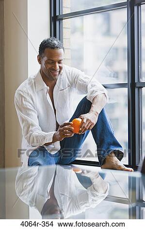 Man relaxing on window sill in loft apartment View Large Photo Image Picture - Man relaxing on window sill in loft apartment. Fotosearch