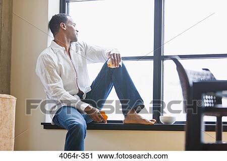 Man relaxing on window sill in loft apartment View Large Photo Image Stock Image - Man relaxing on window sill in loft apartment. Fotosearch