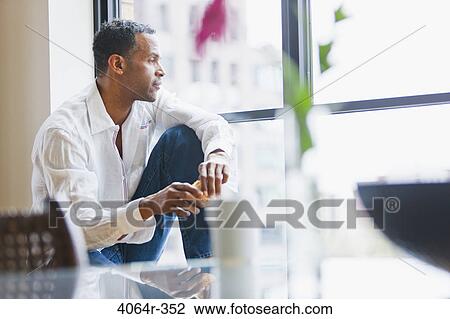 Man relaxing on window sill in loft apartment View Large Photo Image Stock Image - Man relaxing on window sill in loft apartment. Fotosearch