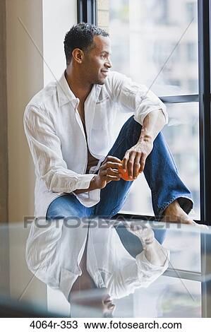Man relaxing on window sill in loft apartment View Large Photo Image Stock Image - Man relaxing on window sill in loft apartment. Fotosearch
