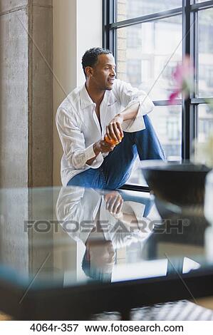 Man relaxing on window sill in loft apartment View Large Photo Image Stock Photo - Man relaxing on window sill in loft apartment. Fotosearch
