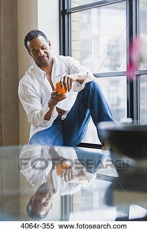 Man relaxing on window sill in loft apartment View Large Photo Image Stock Photography - Man relaxing on window sill in loft apartment. Fotosearch
