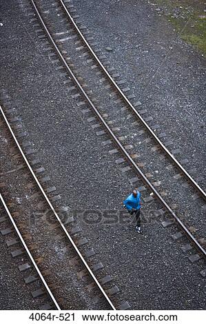 Stock Image - Man running across railroad tracks. Fotosearch