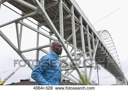 Stock Photo - Man running underneath bridge. Fotosearch