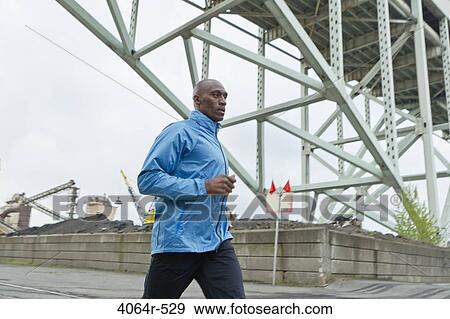 Stock Photo - Man running underneath bridge. Fotosearch