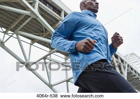 Stock Photo - Man running underneath bridge. Fotosearch
