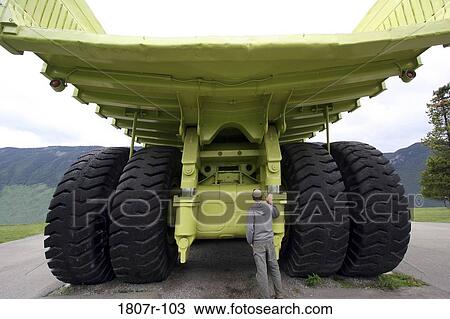 Man standing near an earth mover View Large Photo Image Stock Image - Man standing near an earth mover. Fotosearch