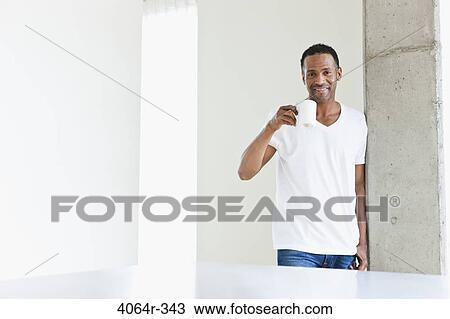 Man standing with coffee cup in loft apartment View Large Photo Image Stock Image - Man standing with coffee cup in loft apartment. Fotosearch