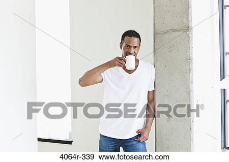 Man standing with coffee cup in loft apartment View Large Photo Image Stock Photo - Man standing with coffee cup in loft apartment. Fotosearch